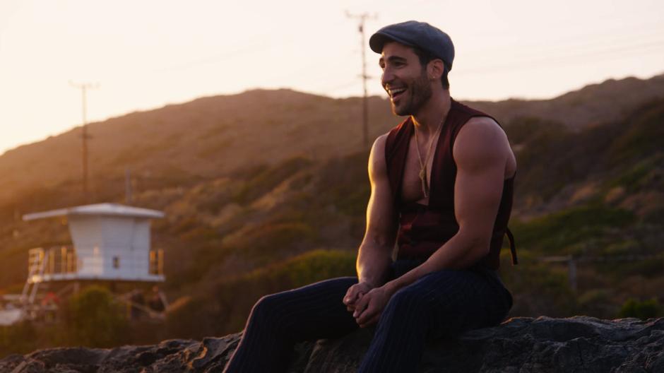 Lito laughs at Hernando's antics in the water while sitting on the sand.