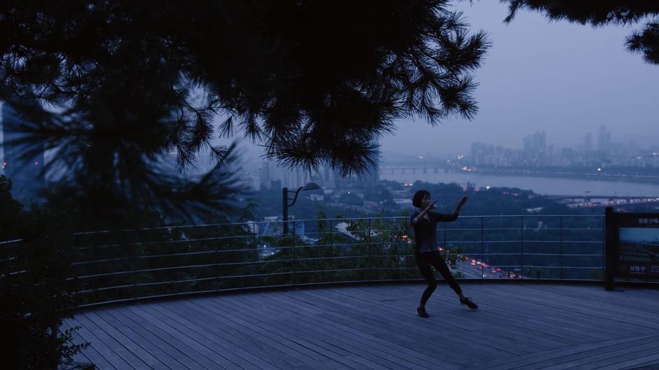 Sun practices on a platform overlooking the river and the fog-covered city.