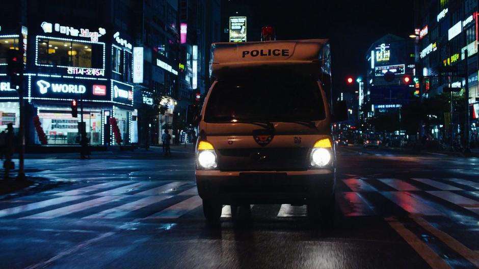 The police transport continues through an intersection.