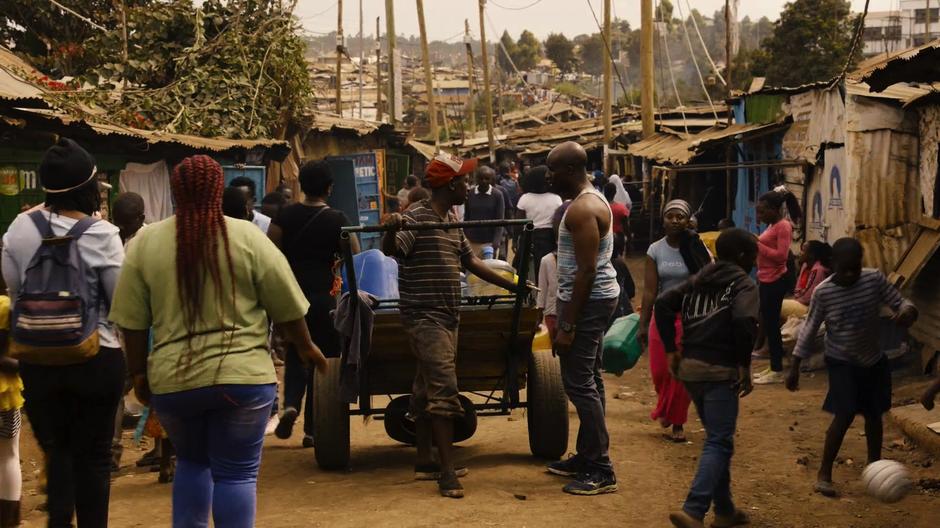 The water seller discusses the price increase with Capheus outside his home.