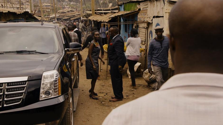 Capheus watches as Silas helps Shiro out of his car.