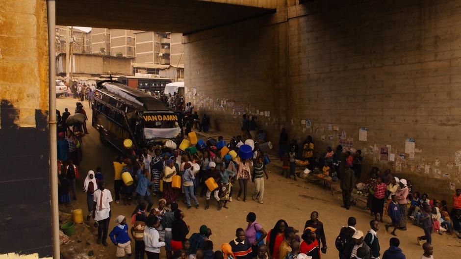 Capheus walks through the group of people in front of the Van Damn under the underpass.