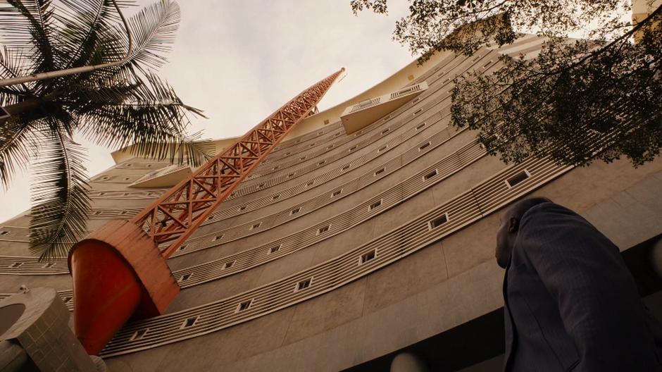 Capheus looks up at the building which has a large red antenna on the front.