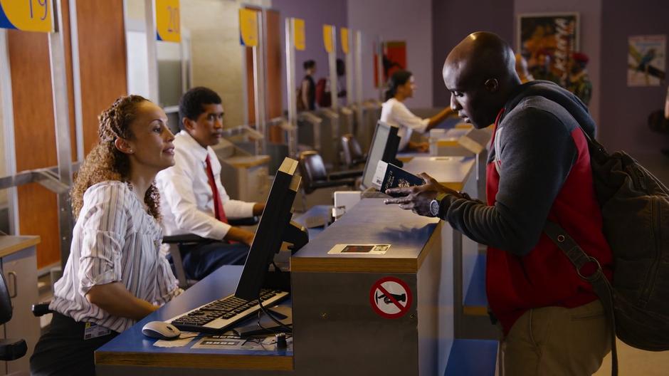 Capheus checks his ticket after it is handed to him by the airline agent.