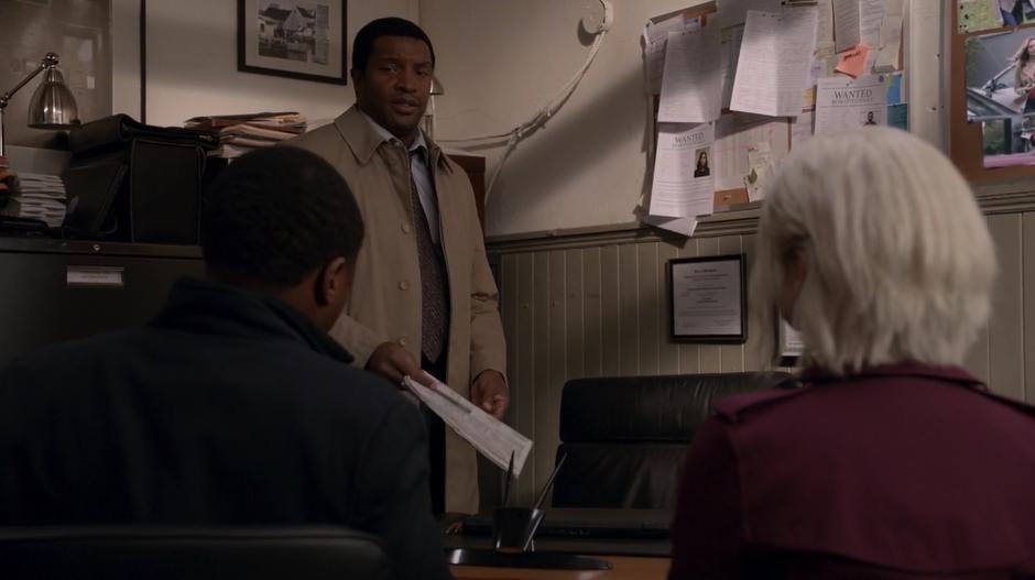 Coleman Baker sets his newspaper down on his desk where Clive and Liv are sitting while Clive asks about the case.