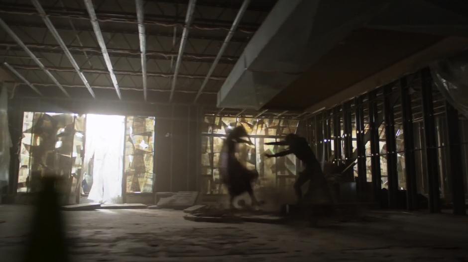 Rhea throws Kara across the interior of the building which is under construction.