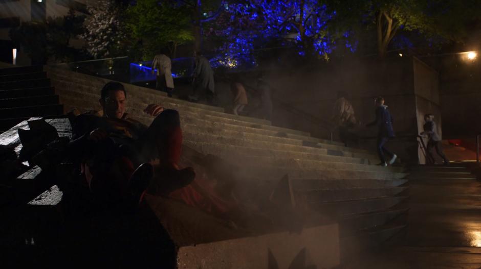 Clark lies against the stairs after being thrown to the ground by Kara.