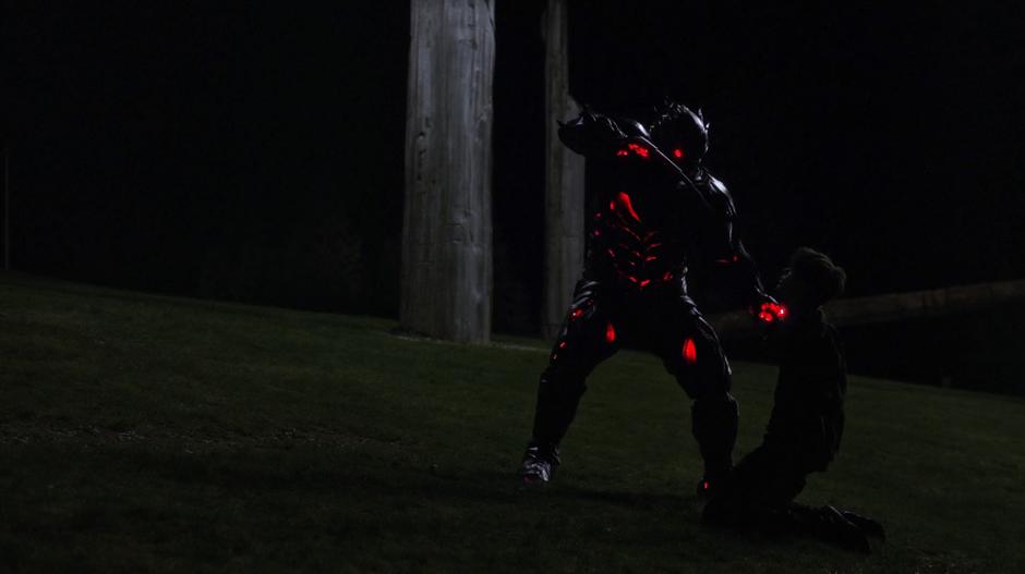 Barry, now occupying the suit, holds out the arm sword at Savitar while holding him on his knees.