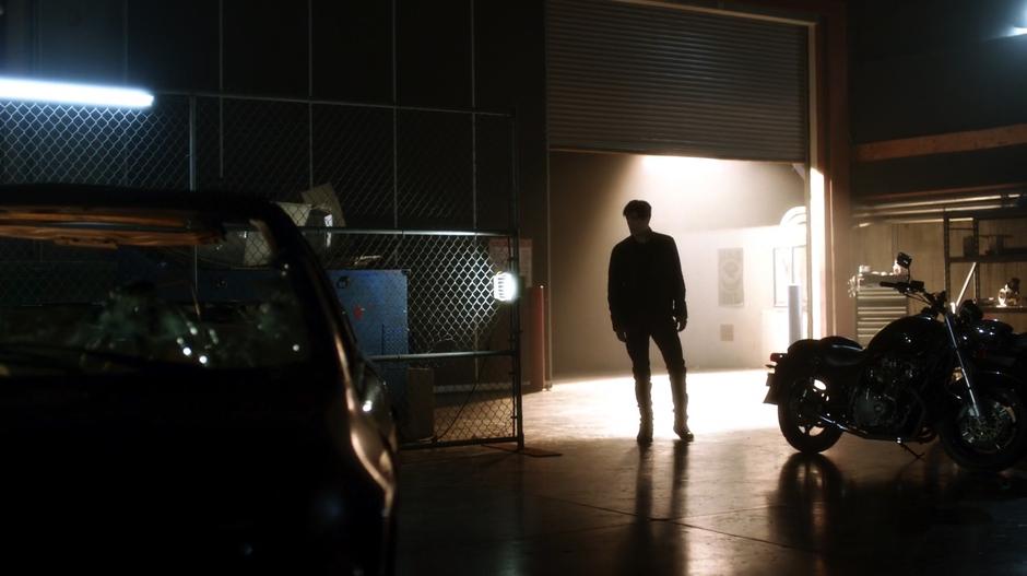 Savitar enters the garage through the open door.