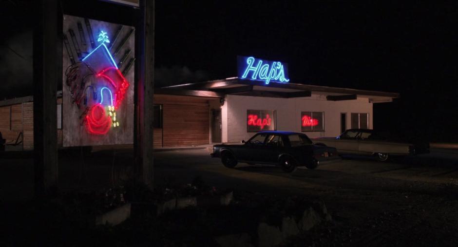 Establishing shot of Hap's Diner with a partially burned out sad clown neon sign.