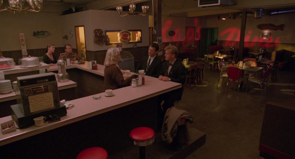 Chet and Sam sit down at the counter as the waitress Irene sets coffees in front of both of them.