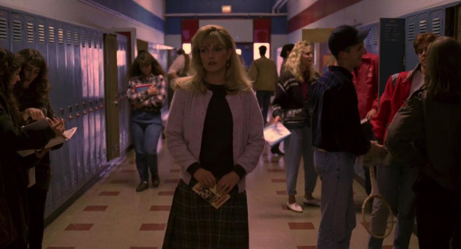 Laura walks down the hallway of the school in a daze.