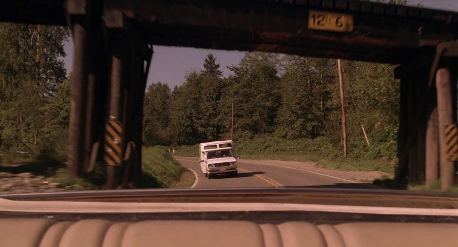 The One-Armed Man's truck approaches Leland's car from behind under the rail bridge.