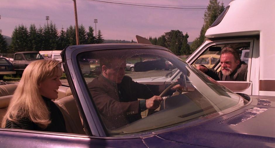 Leland and Laura look ahead as the One-Armed Man barks at their car.