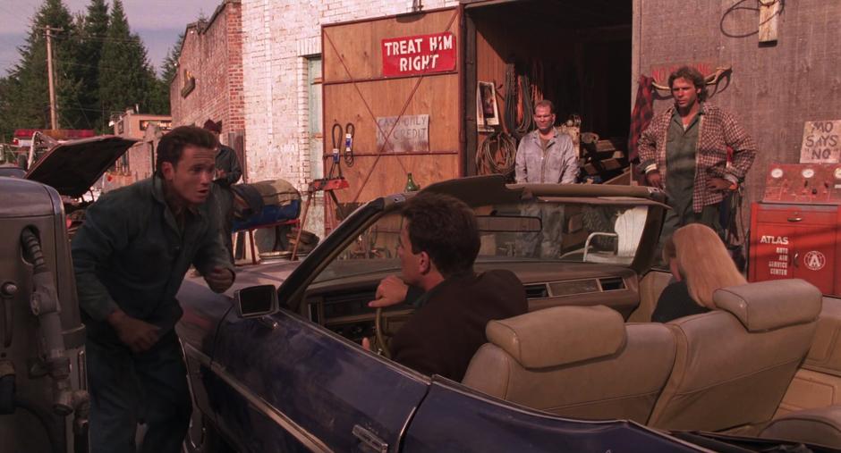 One of the auto shop workers approaches the car after Leland pulls it up in a hurry.