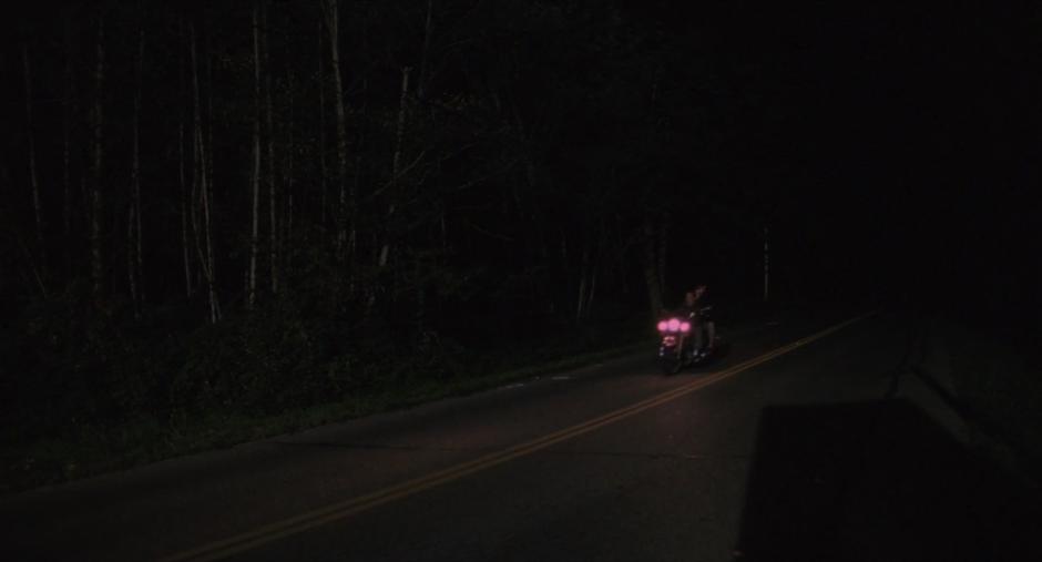 Laura rides down the darkened street on the back of James's motorcycle.