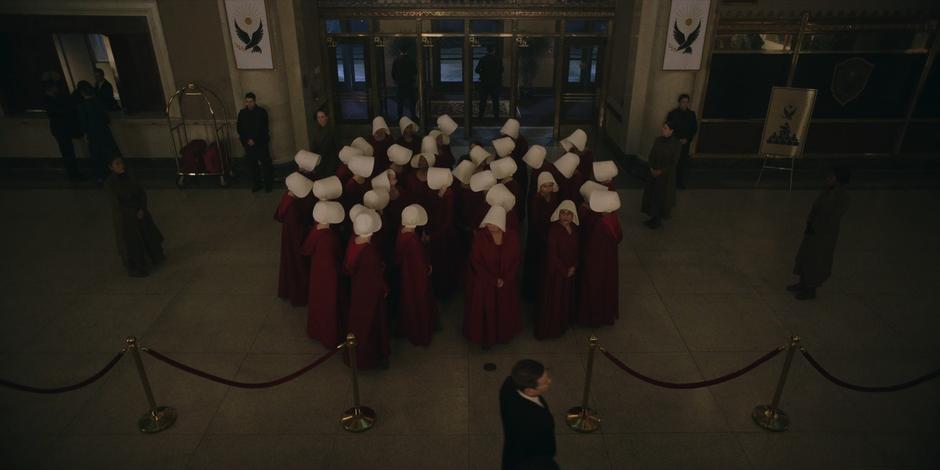 The handmaids mill around in the lobby of the building before the banquet.