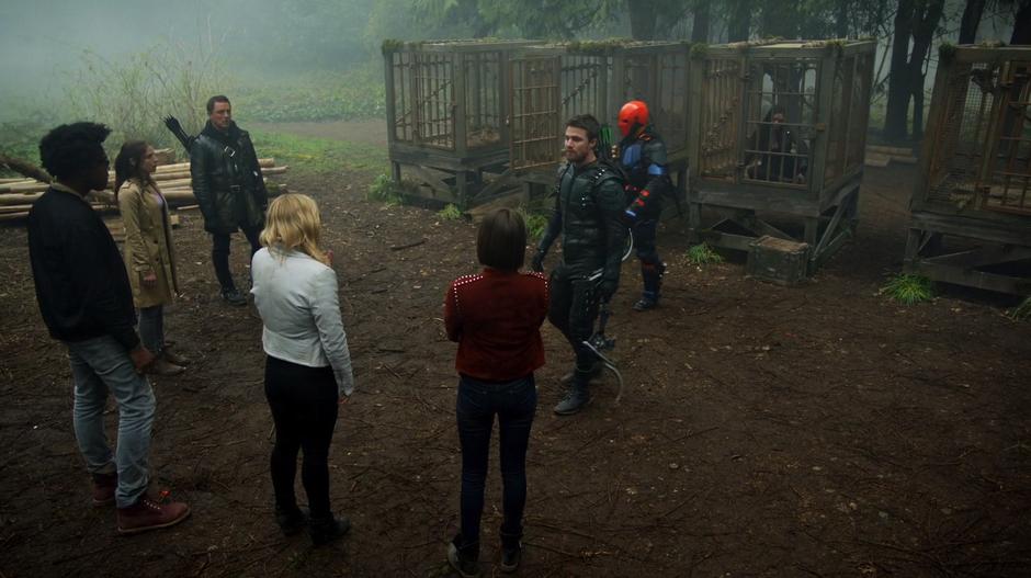 Oliver approaches the group of newly rescued prisoners after locking Evelyn Sharp in one of the cages.