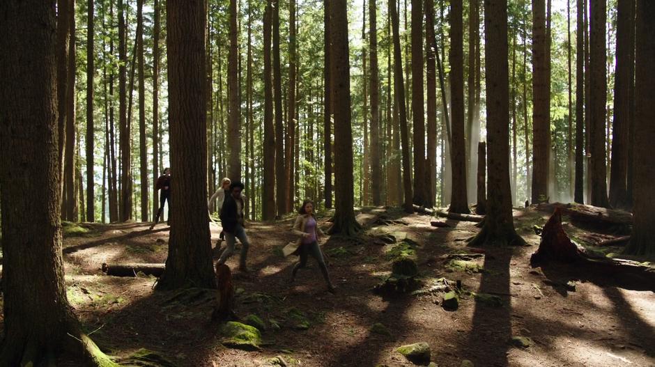 Thea, Felicity, Curtis, and Samantha run through the woods away from where they left Merlyn with the mine.