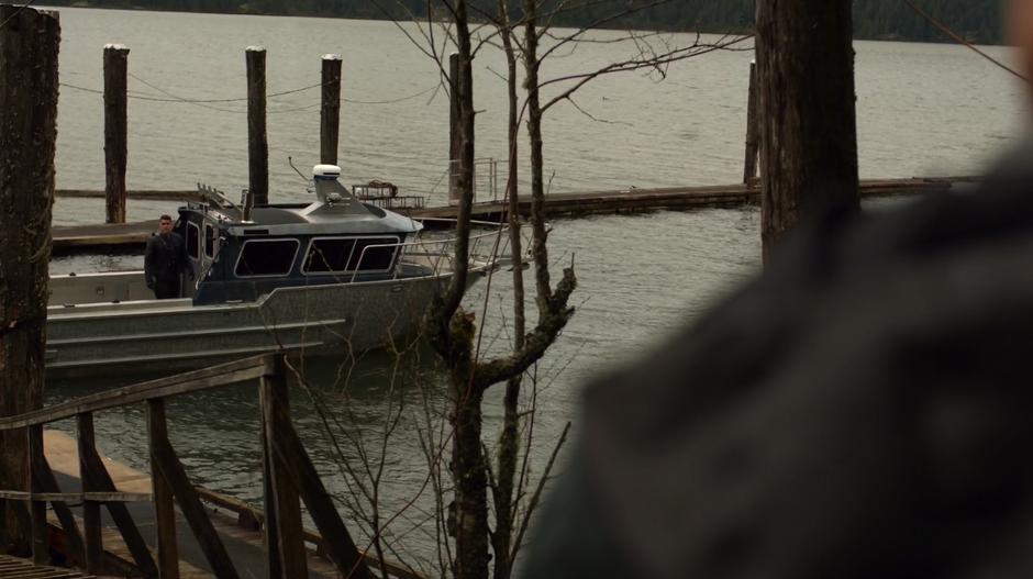 Adrian Chase looks at Oliver from his speed boat at the dock.