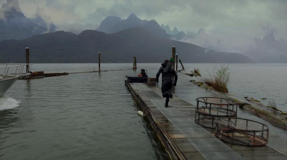 Oliver runs down a dock parallel to where the boat is driving.