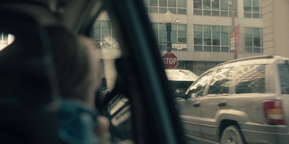 June looks out the window as they drive up to an intersection.