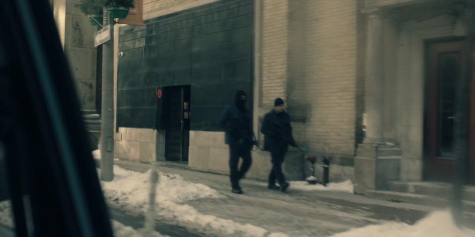 Two guards walk down the snowy street.