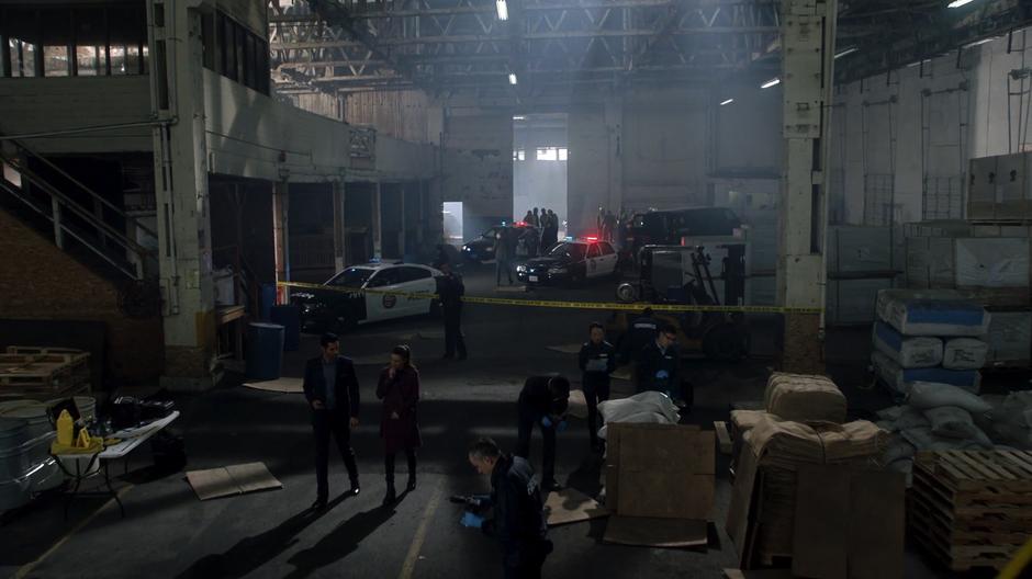 Lucifer and Chloe approach the body while surrounded by crime scene technicians.