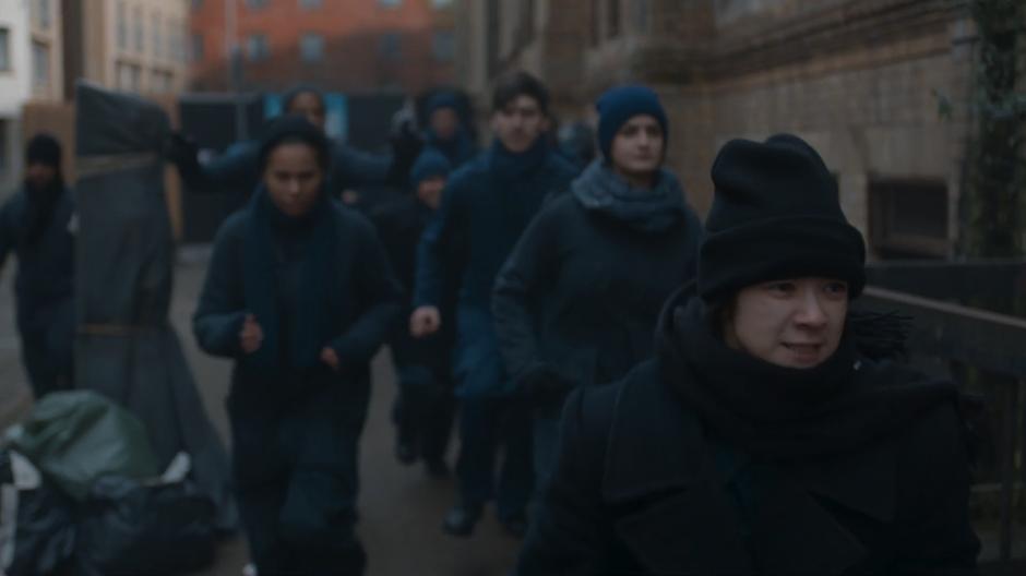 Civilians run down the street towards one of the monks.