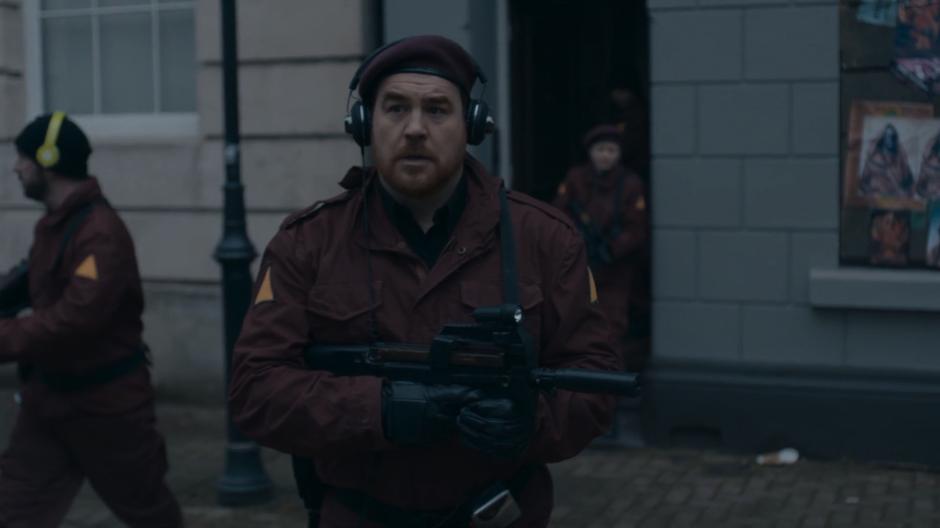 One of the resistance members exits the abandoned building and walks down the street while wearing headphones.