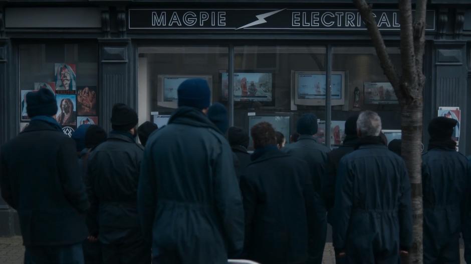 People stand in front of the television store watching the monks' broadcast about an execution.