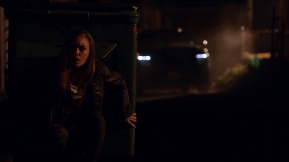 Rachel hides behind a dumpster while the Fillmore Graves mercenaries drive past.