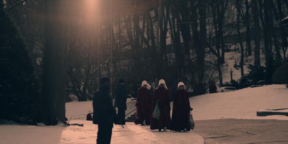 Offred and Ofglen walk home with their shopping bags.