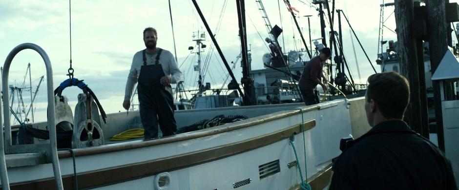 Sam walks up to the edge of the boat to greet the police officer.