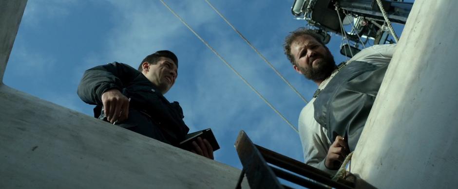 Sam and the cop look down into the hold of the boat.