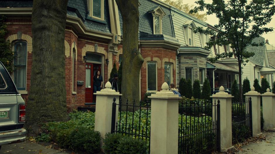 Siobhan watches from the doorway as Sarah walks out on her crutches to where Kira is waiting to go to school.