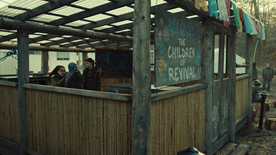 Charlotte watches while Cosima examines Aisha in the school building.