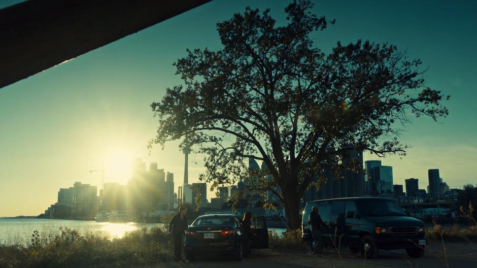 Felix and Siobhan get out of their car on the waterfront near where the smuggler's are waiting with their van.