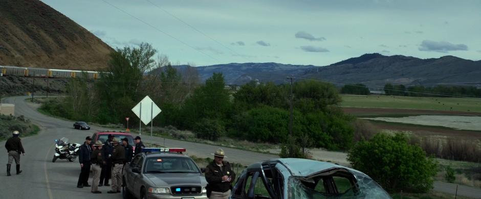 The car with Billy, Kimberly, and Jason drives past as the police stand around the crash site and the destroyed car.