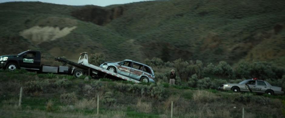 The police investigate the scene while Billy's mom's destroyed van is loaded onto a truck.