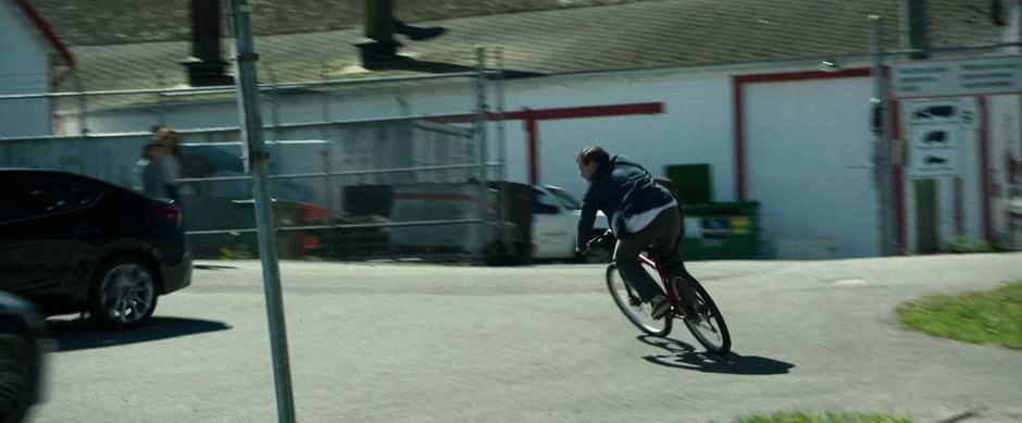 Jason turns the corner on his bike and rides past two women out walking.