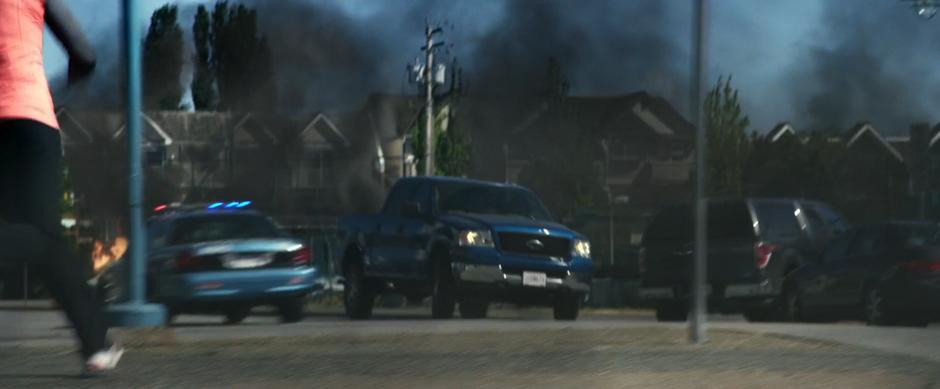 Sam swerves to avoid a police car while driving down the street towards the battle.