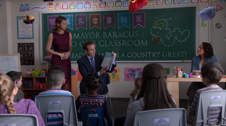 Peyton walks up to Floyd Baracus who is reading from a book in front of a group of young students.