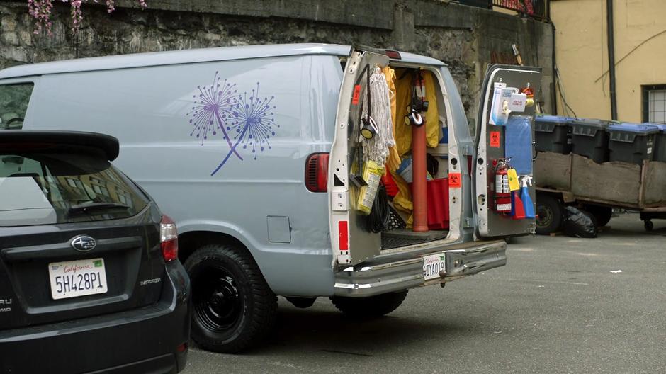 The cleaning company van sits parked in the lot with the back doors open.