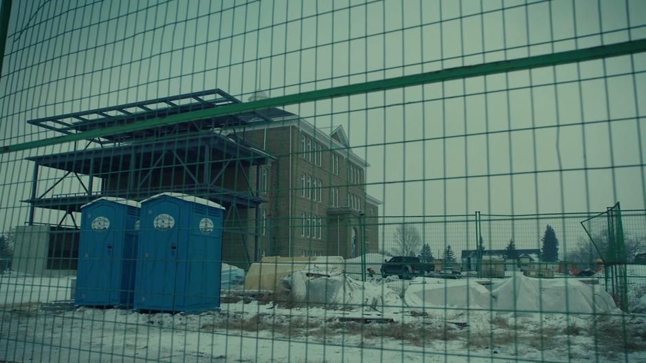 Construction workers mill around the site while two Porta-Potties sit out front.