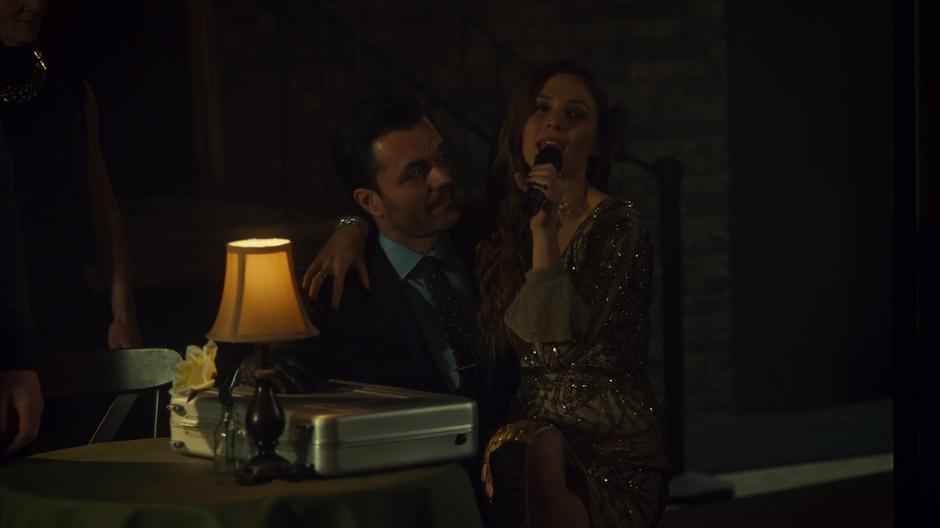 Waverly sits on Jaxon's lap during her song while he sits at the table with the stolen briefcase.