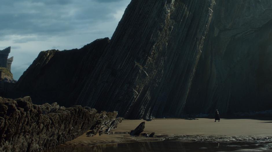 Daenerys walks across the beach towards the castle.