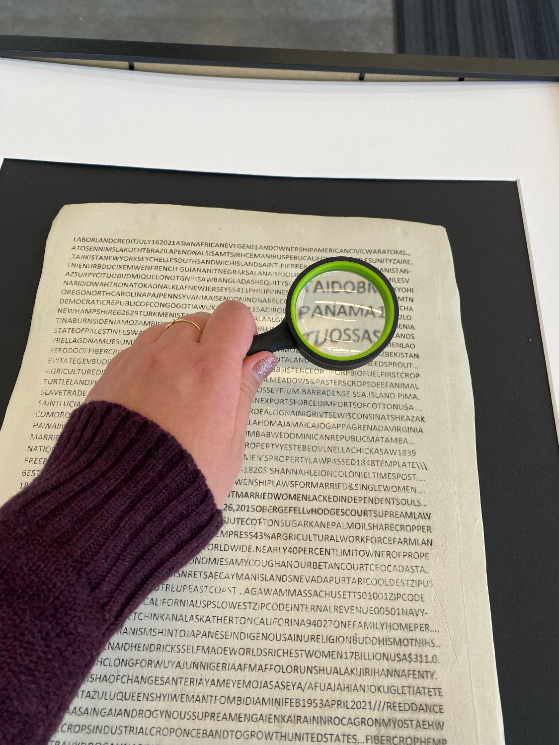 A hand holds a magnifying lens over a page of scrambled letters, highlighting the word "Panama"