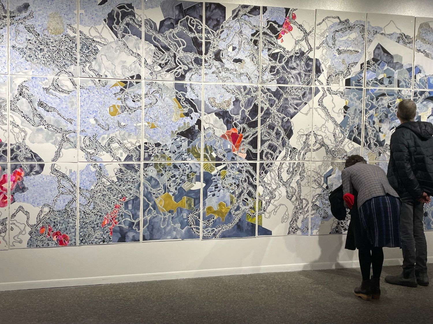 Two people closely inspect a large abstract work of art