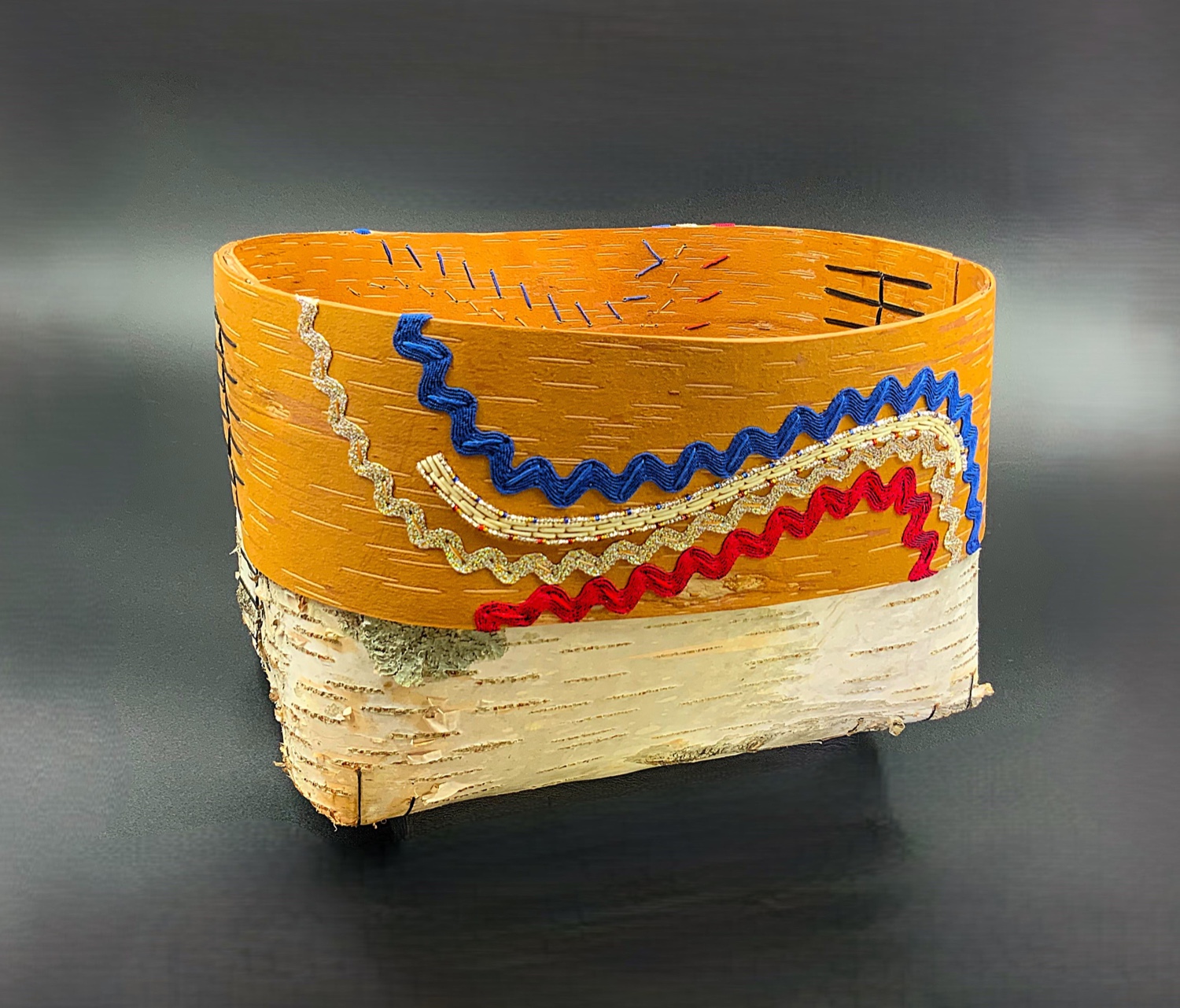 Small handwoven basket with blue and beige beadwork on yellow